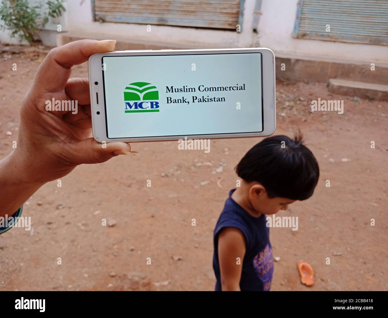 DISTRICT KATNI, INDIA - JUNE 02, 2020: An indian woman holding smart phone with displaying MCB muslim commercial bank limited logo on screen, modern b Stock Photo