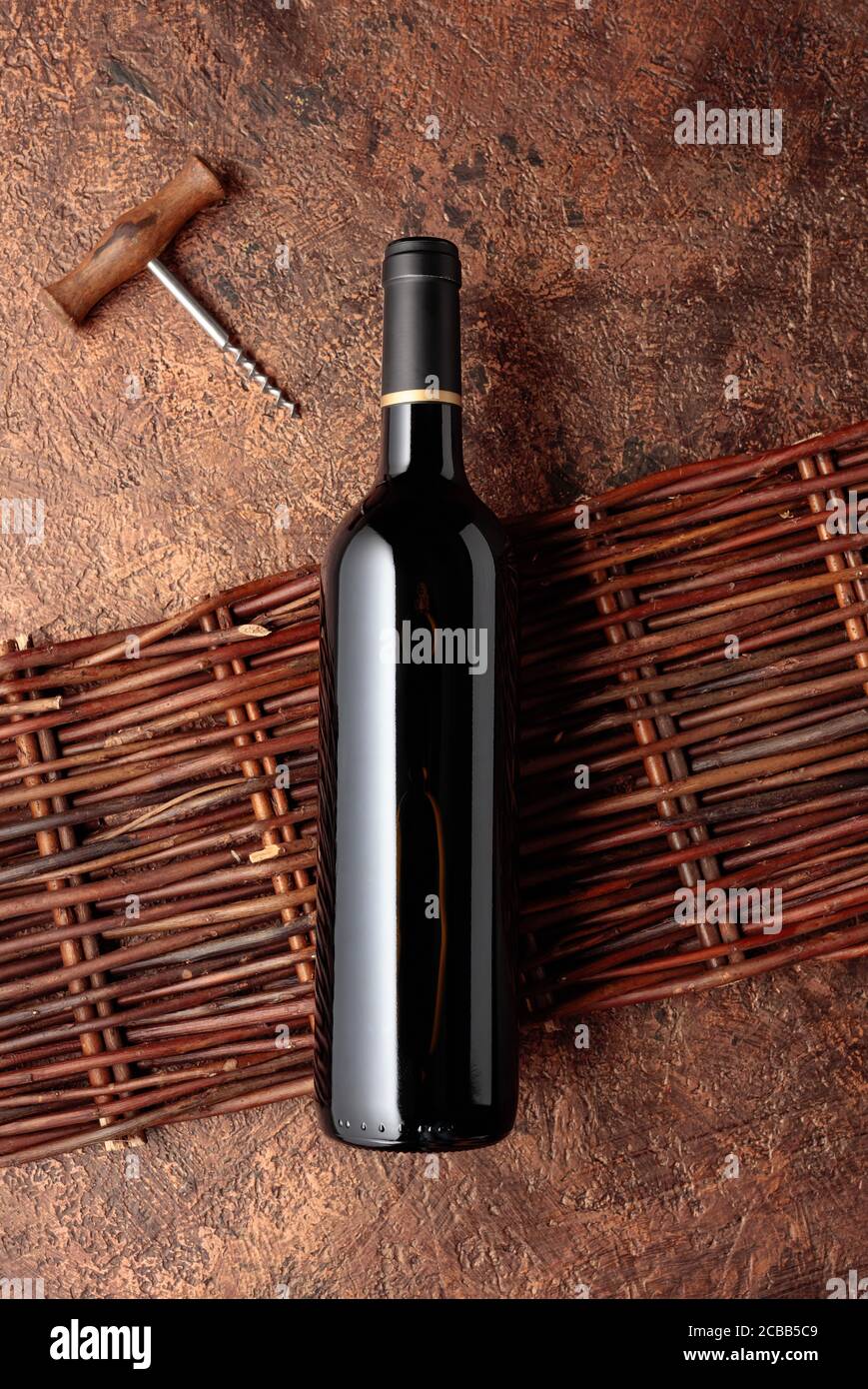 A bottle of red wine on an old rough background with a wicker fence