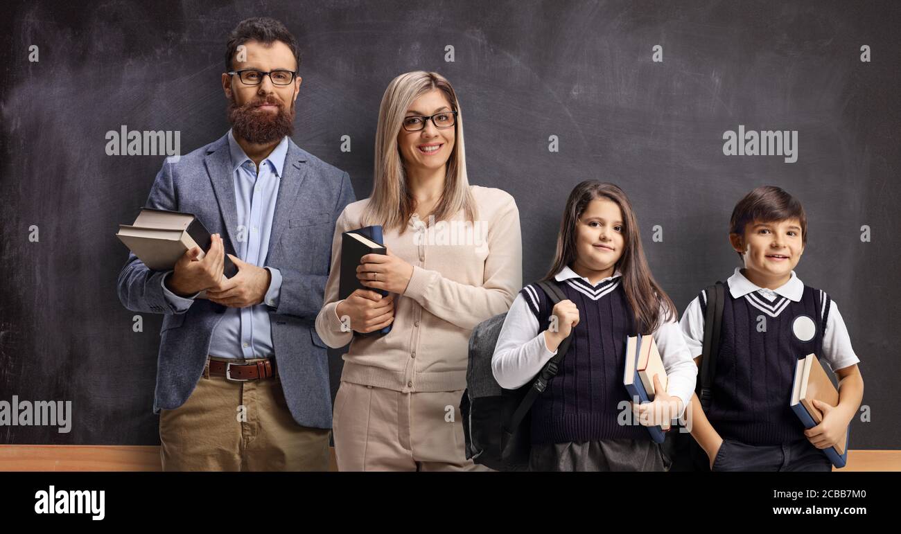 Male and female teacher with pupils standing in front of a school ...