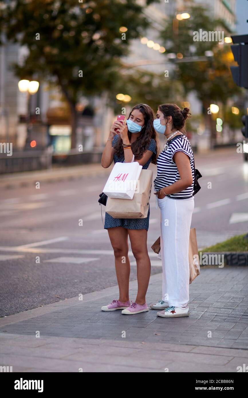 Madrid, Spain - August 8, 2020: Tourists and walkers walk through the city of in a sunset in the city of Madrid. People wear a mask to protect yoursel Stock Photo