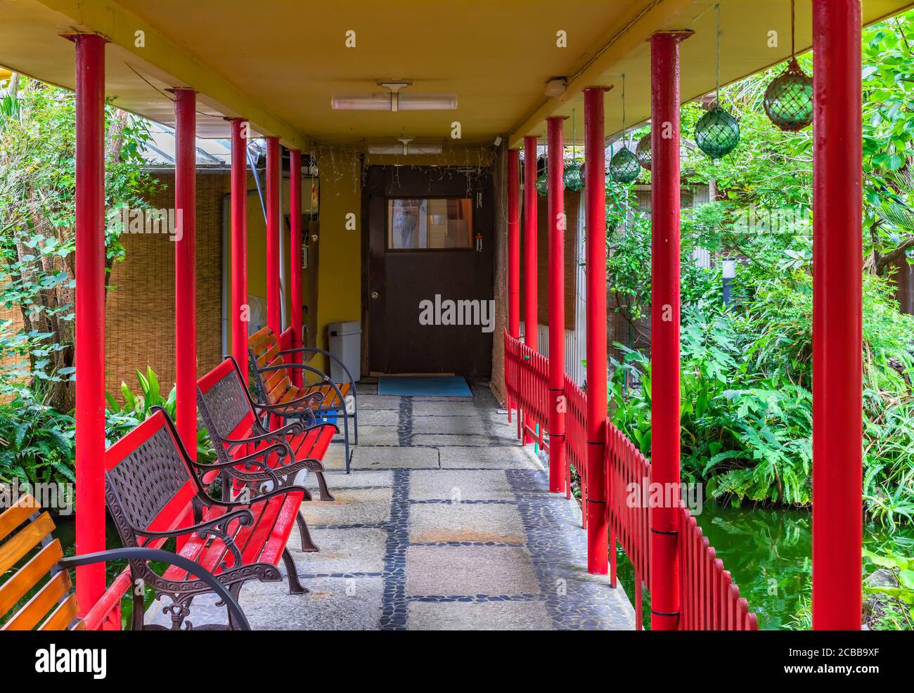 chiba, japan - july 18 2020: Hallway leading through the garden pond of a ryokan guesthouse to onsen hot spring surrounded by benches, pillars and jap Stock Photo