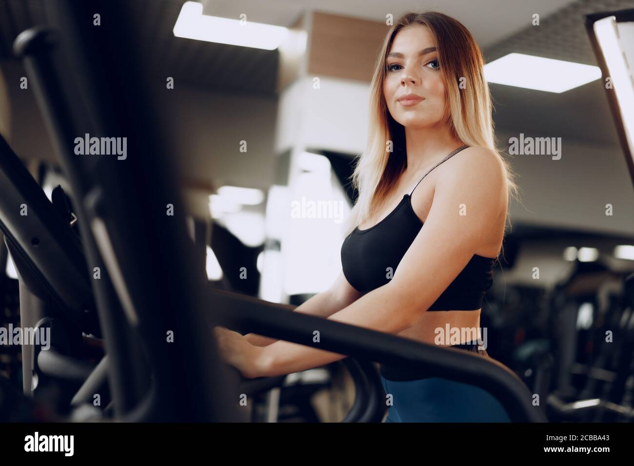 Fit curvy young blonde woman training in a cardio zone in a gym