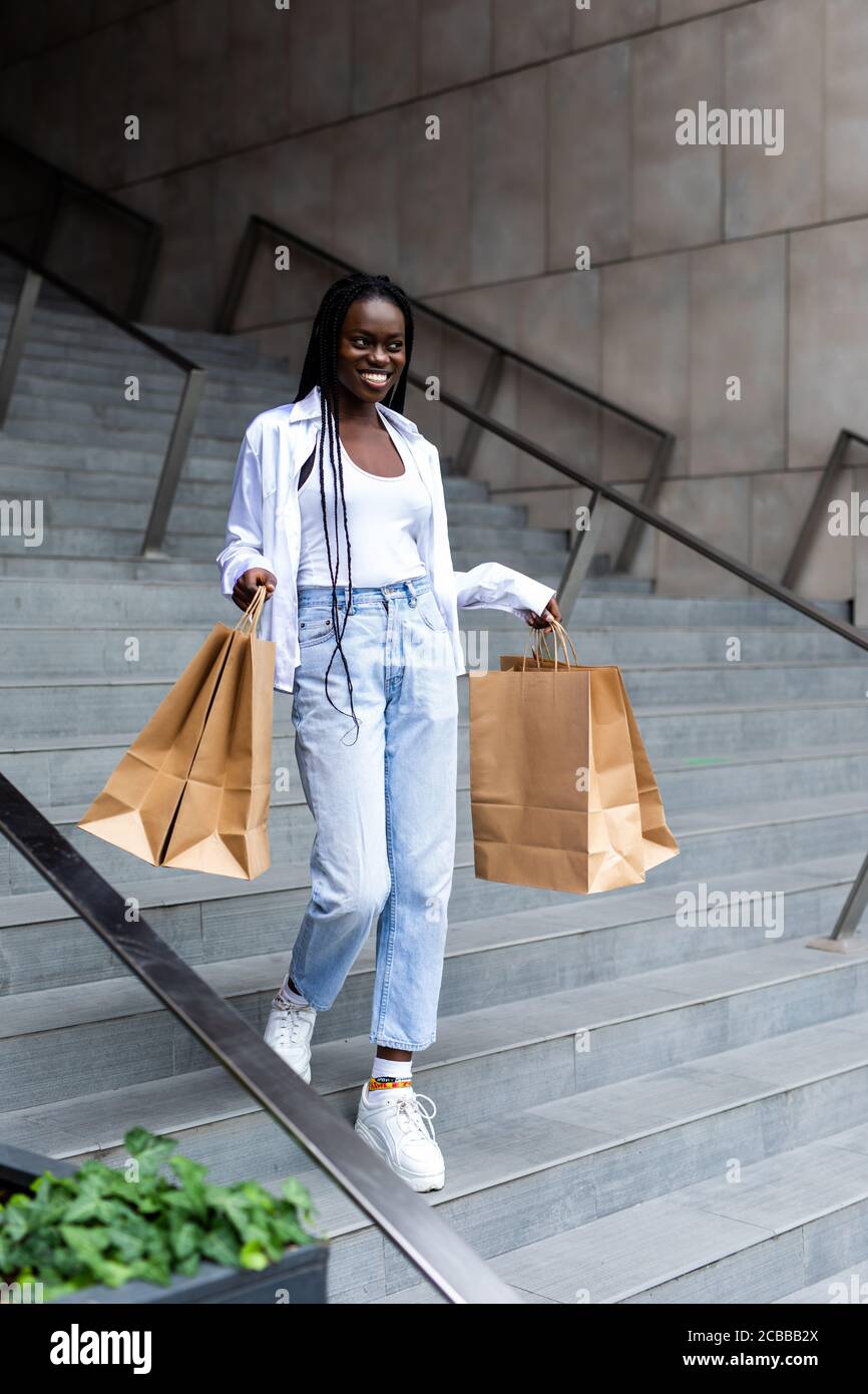 Beautiful black woman smiling and holding shopping bags Stock Photo - Alamy
