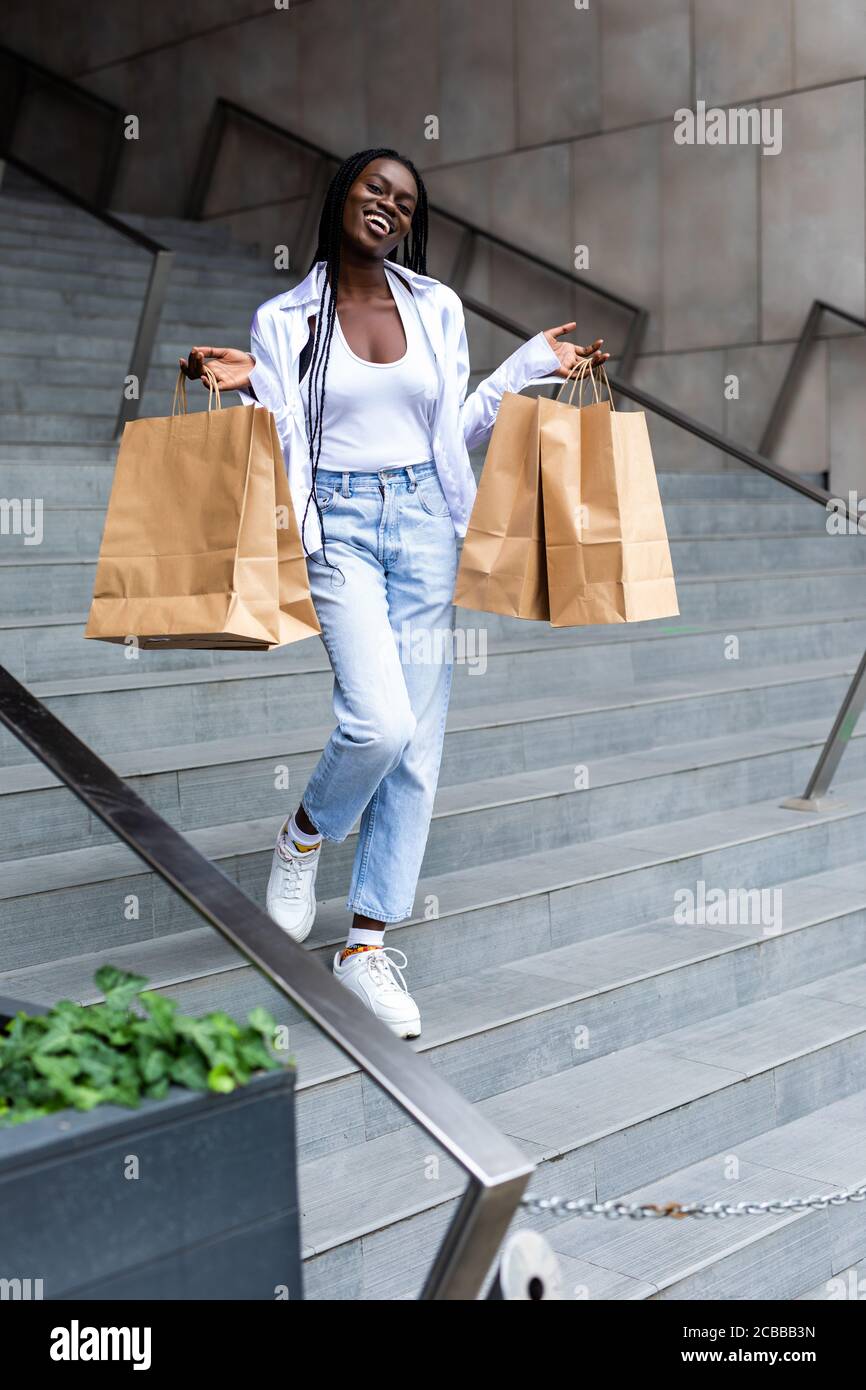 Beautiful black woman smiling and holding shopping bags Stock Photo - Alamy