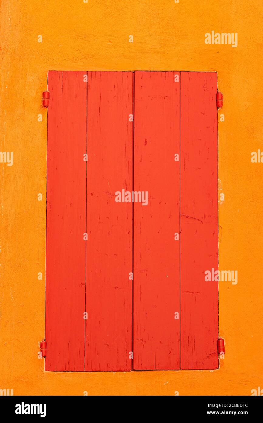 Red shutters against an orange wall in the french village of Roussillon Stock Photo