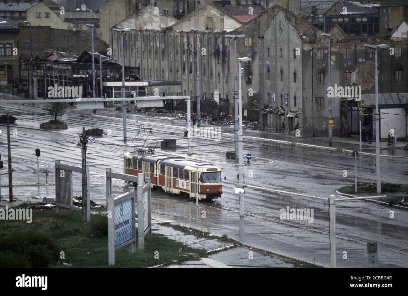 10th April 1994 During the Siege of Sarajevo: only recently running again,  a tram drives west along Vojvode Radomira Putnika, past the ruins of the  old tobacco factory Stock Photo