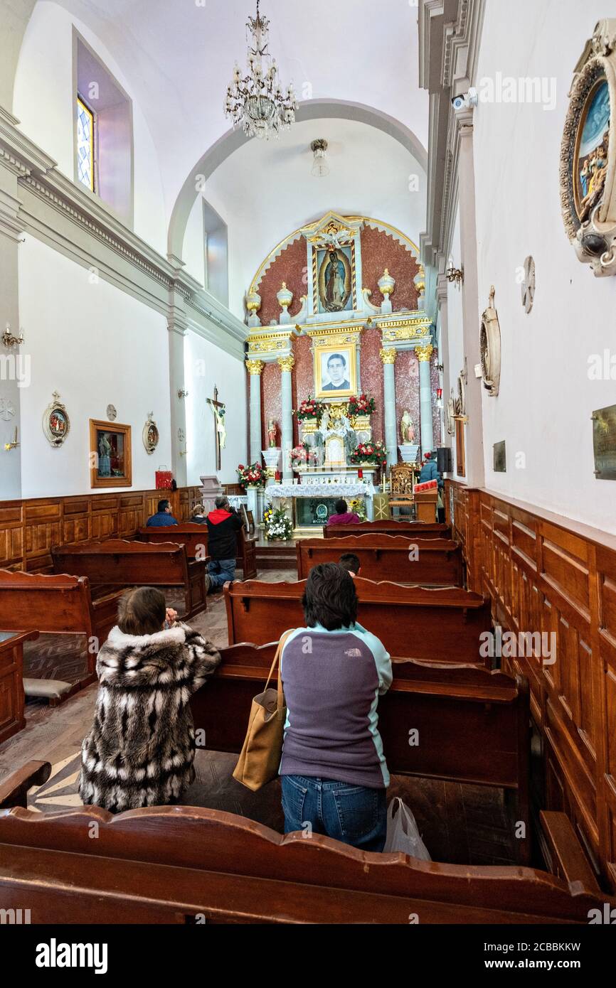 Pilgrims pray in the chapel where Saint Toribio Romo was the parish priest in Santa Ana de Guadalupe, Jalisco State, Mexico. Father Toribio was a Mexican Catholic priest and martyr who was killed during the anti-clerical persecutions of the Cristero War. Stock Photo
