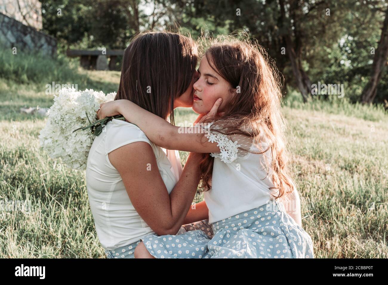 Young mother and her little daughter hugging. Outdoor photo Stock Photo