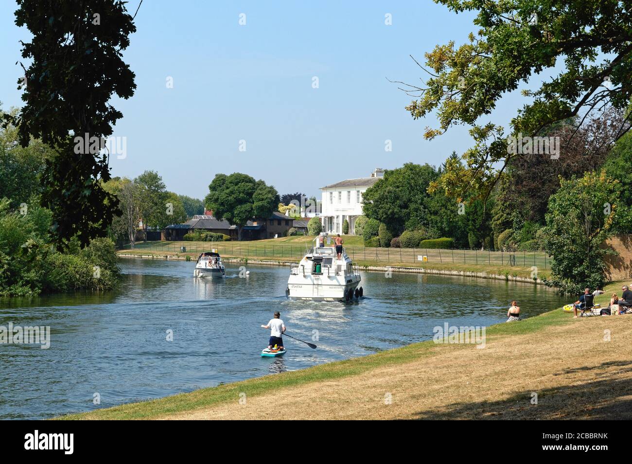 Paddle boarder and motor cruisers on the River Thames at Shepperton on a hot summers day,Surrey England UK Stock Photo