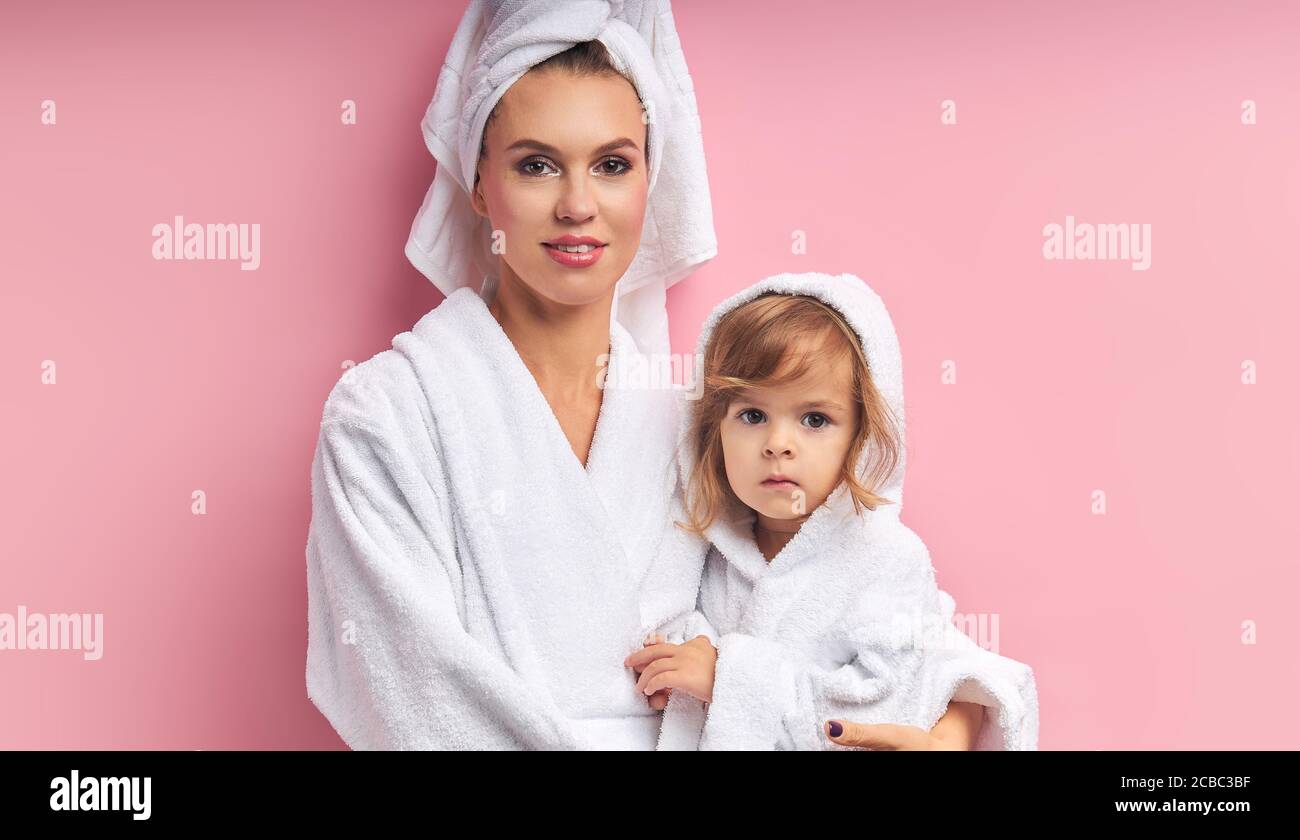 Mother care after bathing. Young mom holding her baby daughter dressed