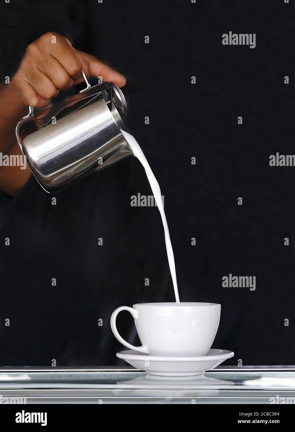 Milk being poured in the white cup by someone Stock Photo Alamy