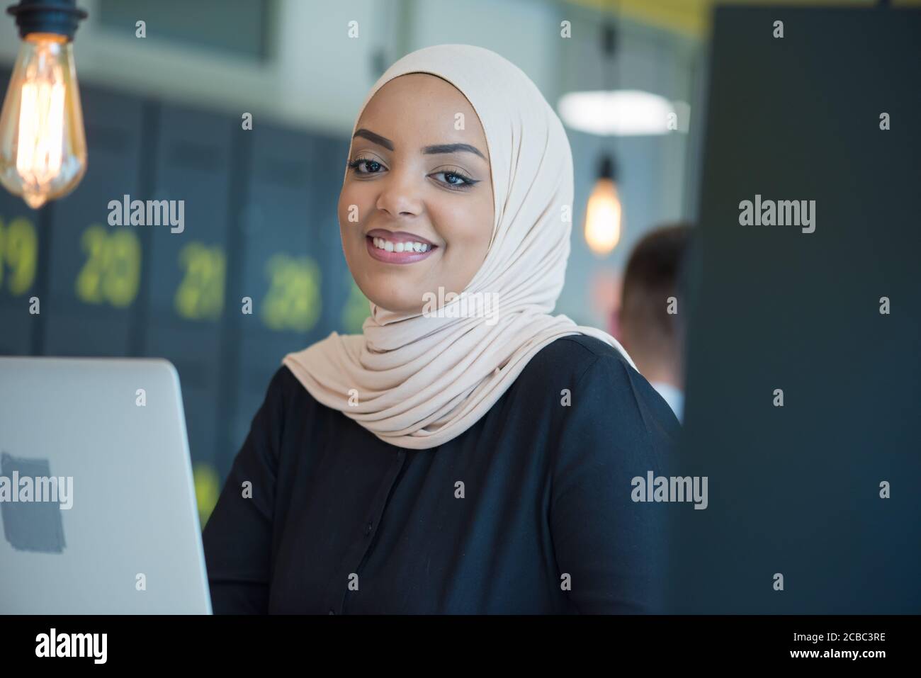 Muslim business lady wearing hijab and working at computer in office ...