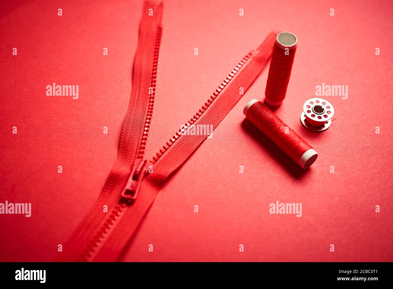 threads and zipper on a red minimalistic background Stock Photo