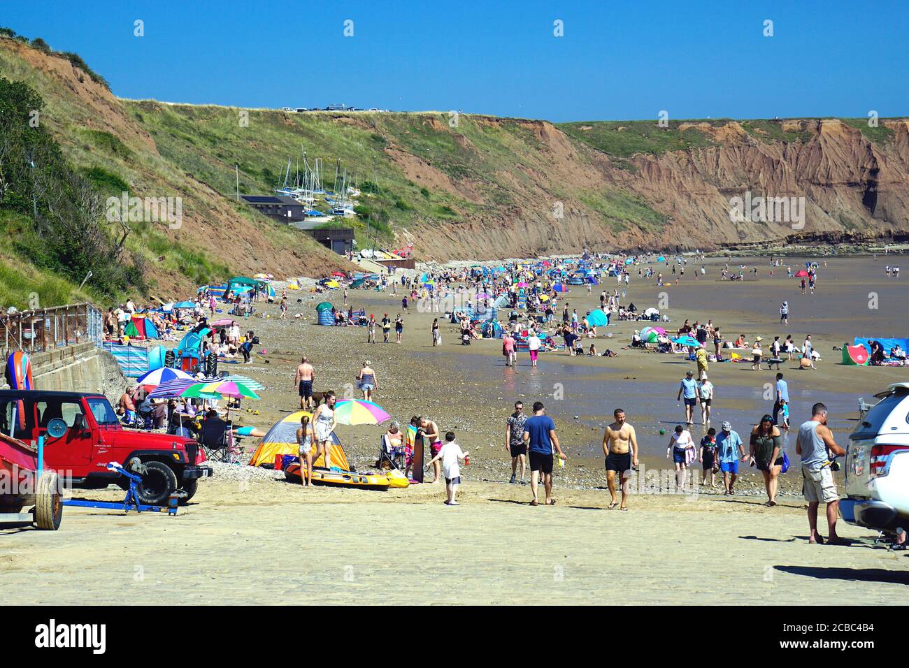 Filey, Yorkshire, UK. August 07, 2020.  Families of holidaymakers after the Corvid-19 lockdown enjoying the beach on Coble landing at Filey in Yorkshi Stock Photo