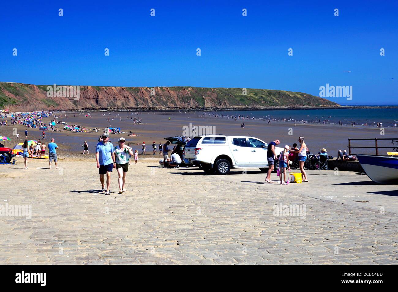 Filey, Yorkshire, UK.August 07, 2020. Holidaymakers enjoying freedom and sunshine after the Covid-19 lockdown with the Brigg in the background Stock Photo