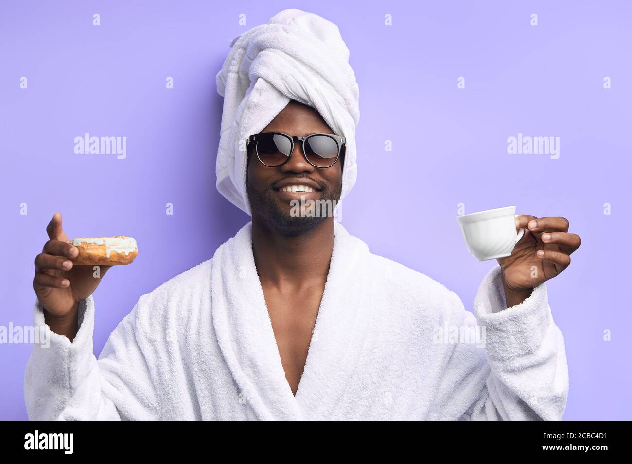 Handsome attractive man in towel and bathrobe holding cup of tea and