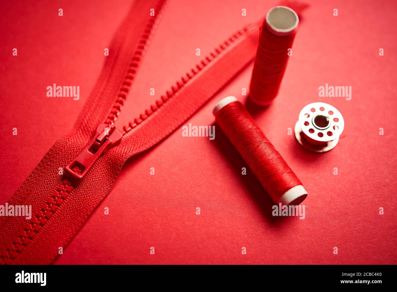 threads and zipper on a red minimalistic background Stock Photo