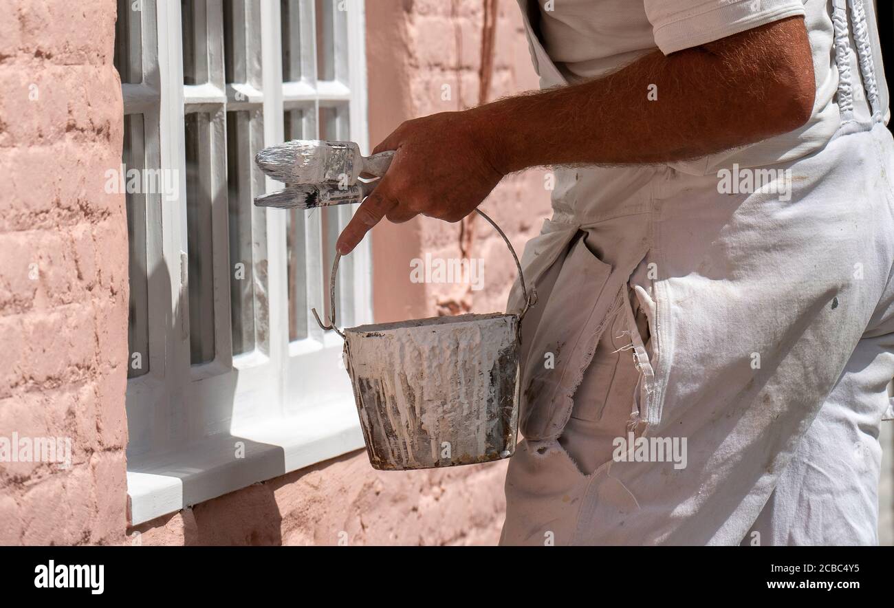 Hampshire, England, UK. 2020. Painter decorator painting small windows on a rural house. Painters kettle and brushes. Stock Photo