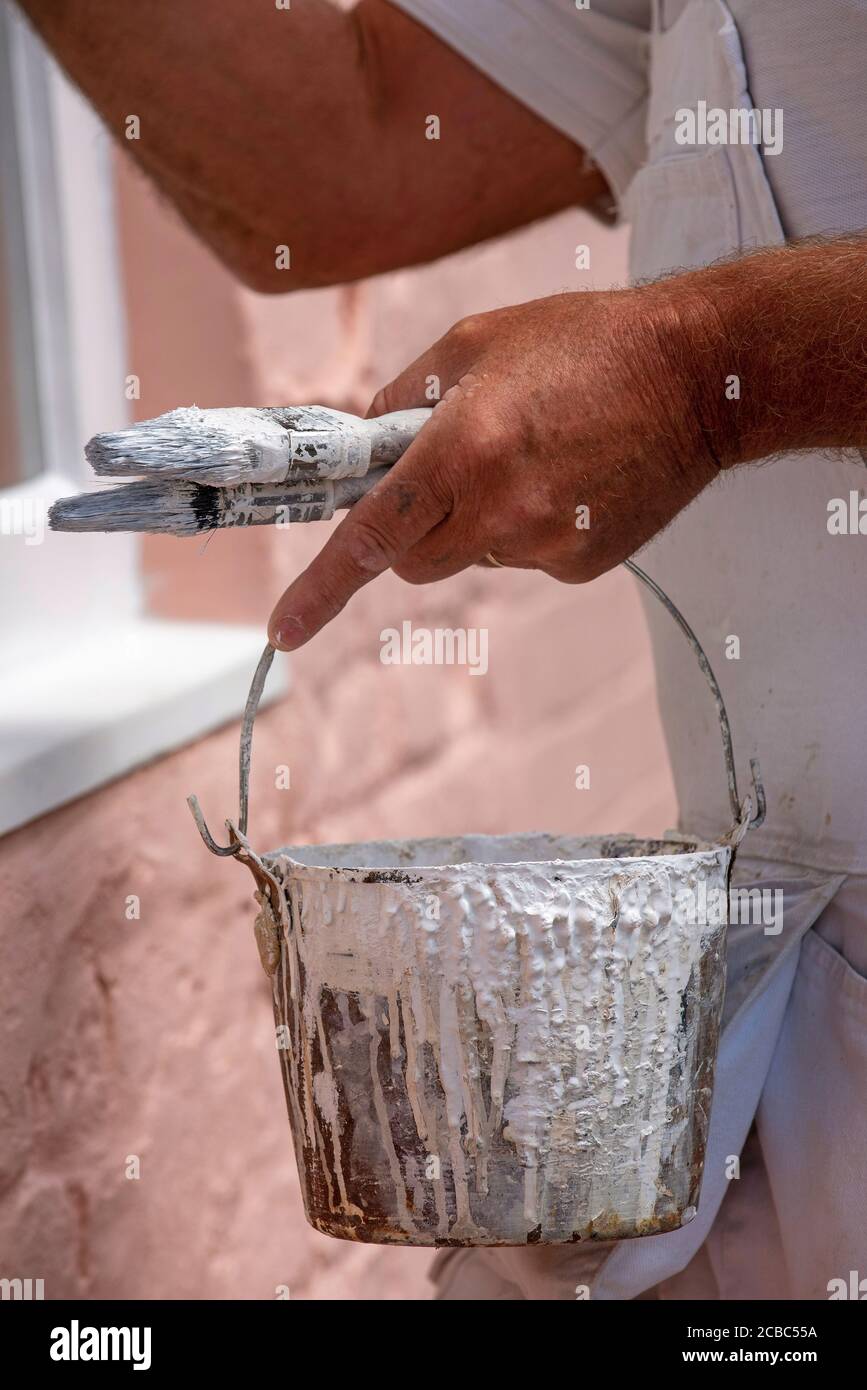 Hampshire, England, UK. 2020. Painter decorator painting small windows on a rural house. Painters kettle and brushes. Stock Photo