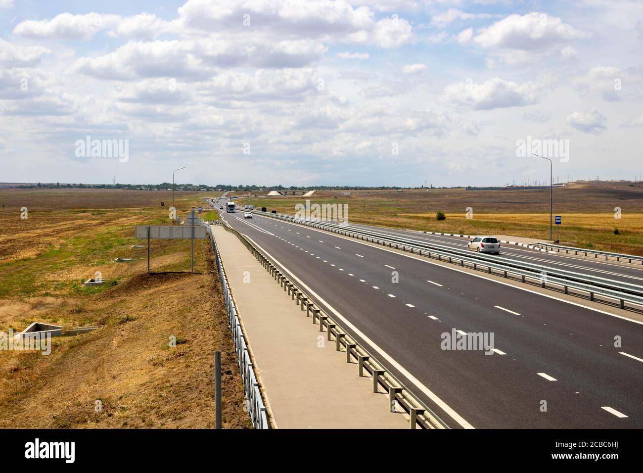 highway in steppe against a blue sky,long road stretching out into the distance. Stock Photo
