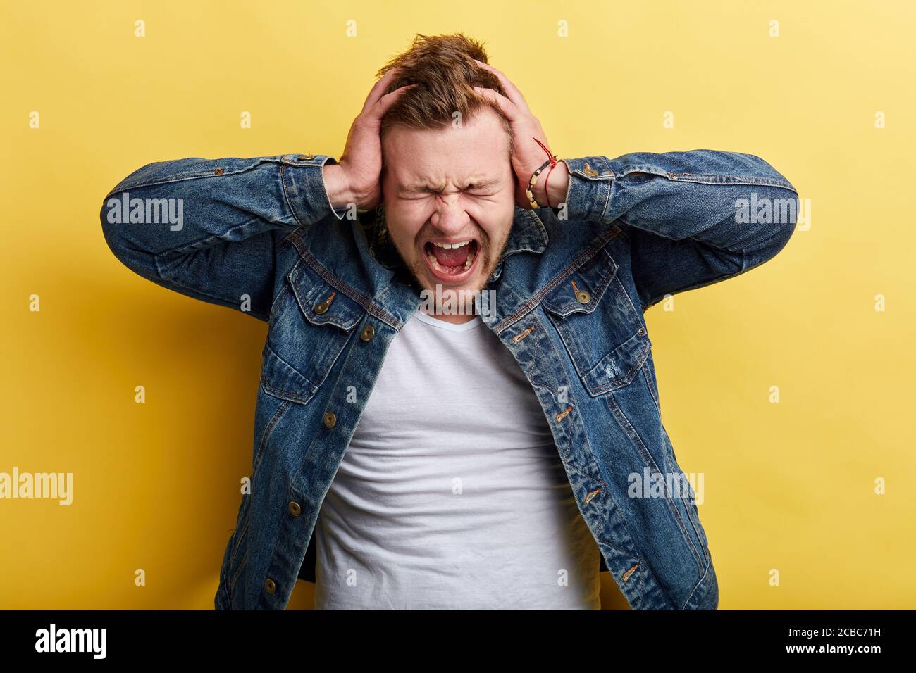 Angry crazy furious frustrated man shouting holding his head with hands