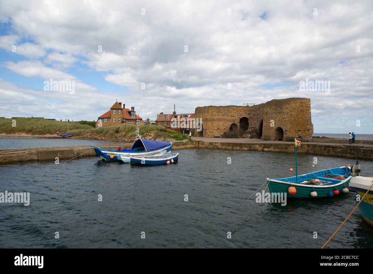 Boats in harbour with historic lime kilns, Beadnell Bay, Northumberland, UK Stock Photo