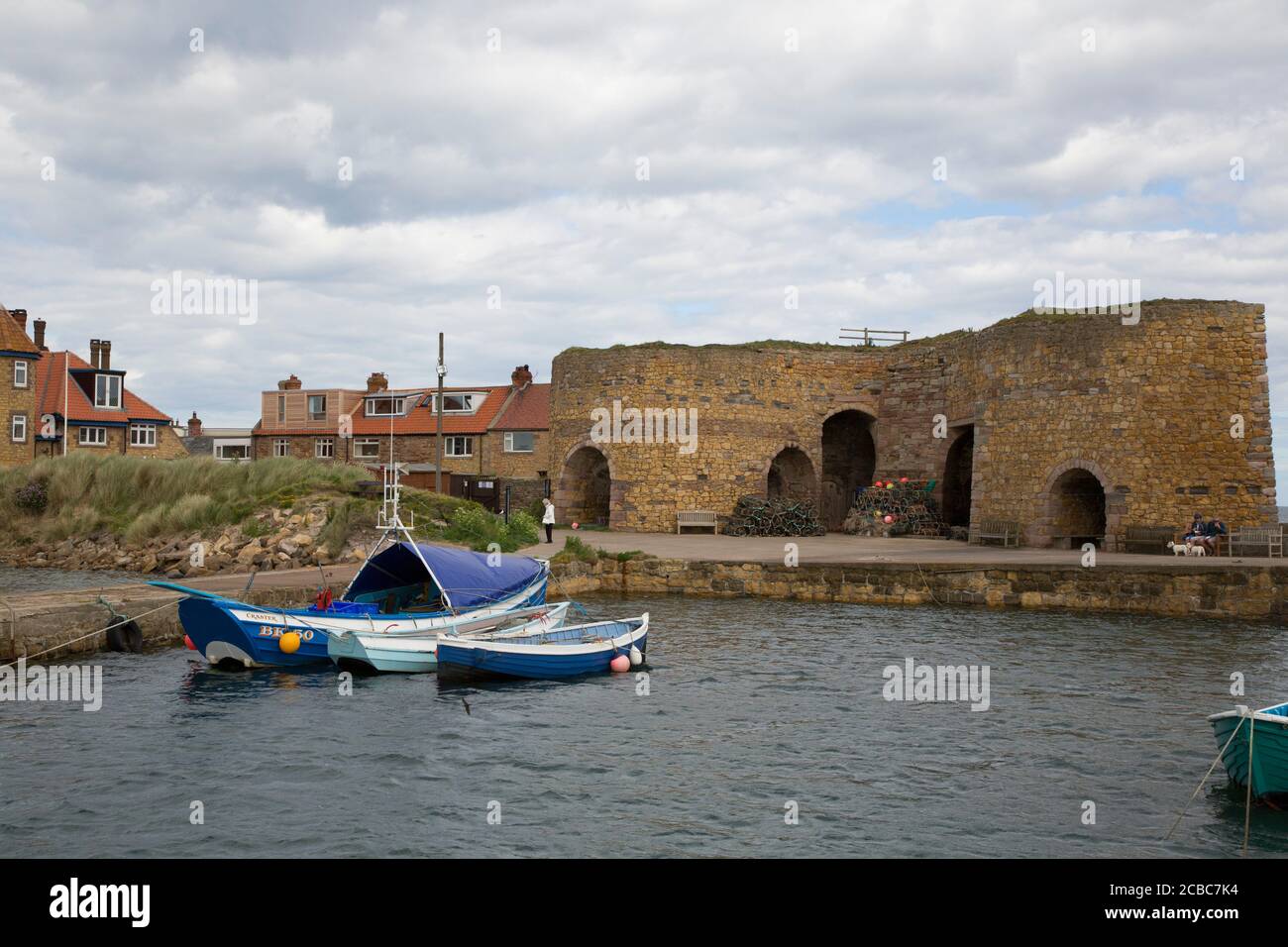 Boats in harbour with historic lime kilns, Beadnell Bay, Northumberland, UK Stock Photo