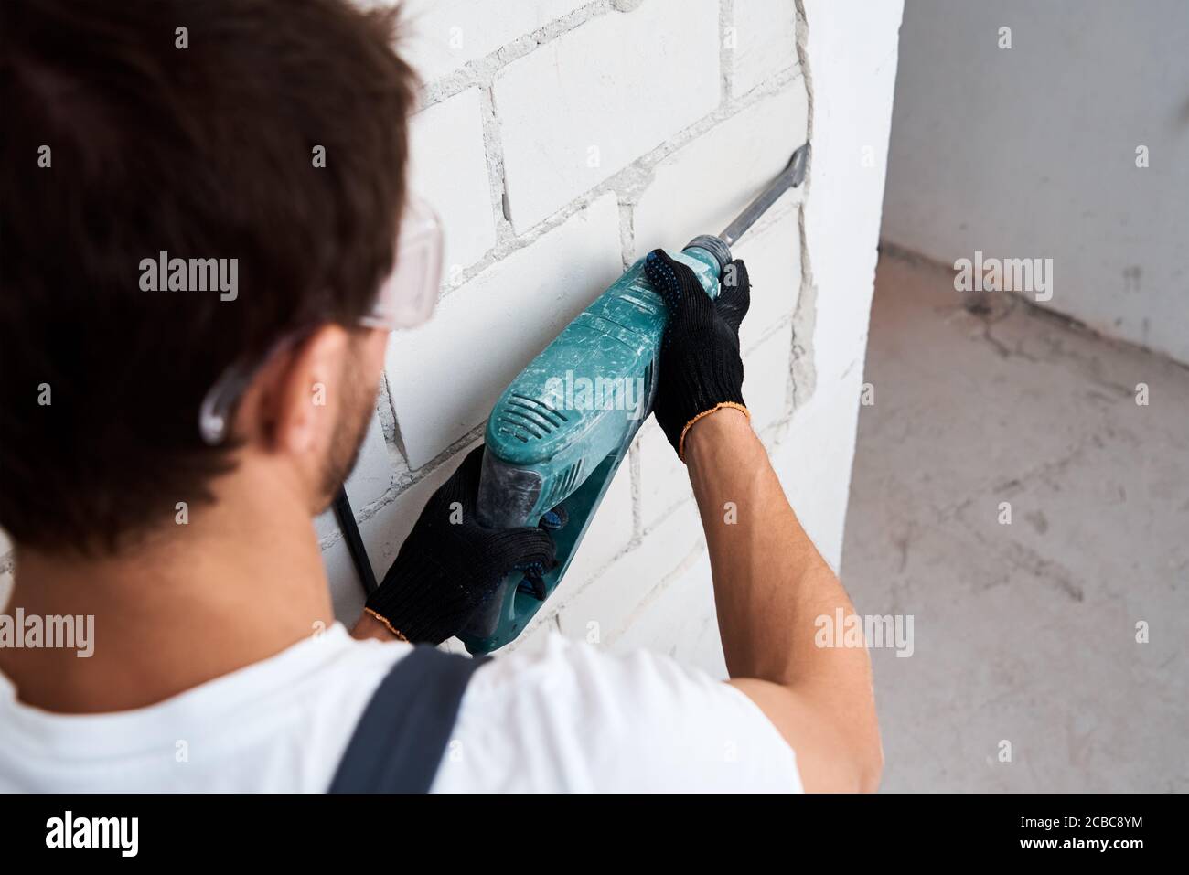 Renovation concept. Man with demolition hammer remove stucco from wall