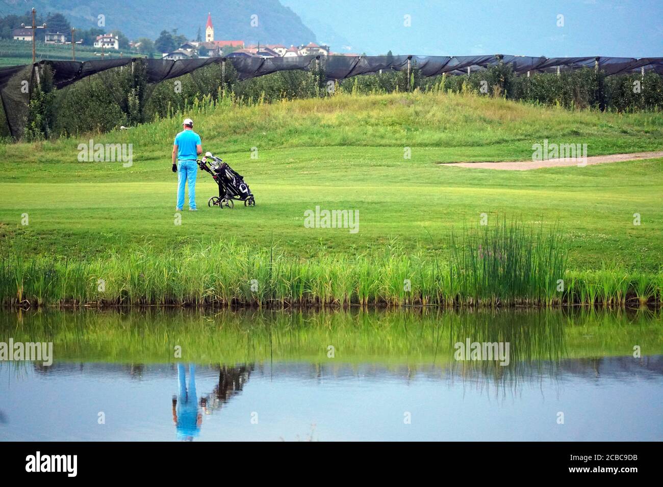 Golfer with golf cart watching a partner at the Blue Monster golf club in South Tirol, Italy. Stock Photo