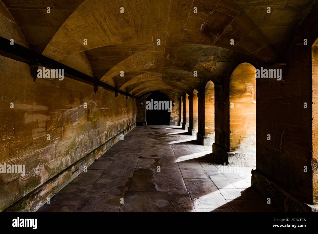 Paved Portico with Arches Leading to a Distant Doorway Stock Photo