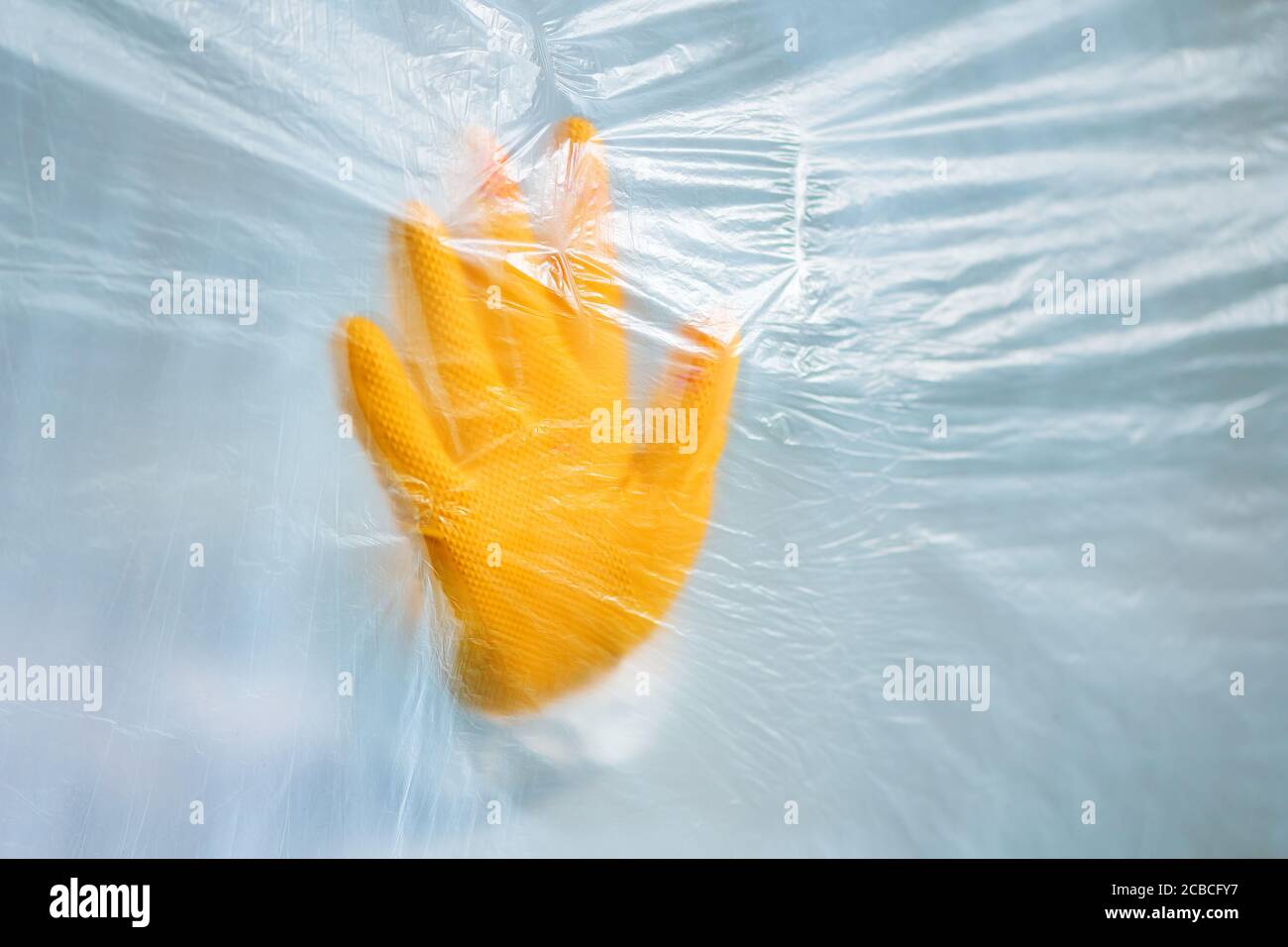 Protective glove behind the plastic curtain in virus quarantine, medical professional epidemiologist fighting the viral outbreak Stock Photo