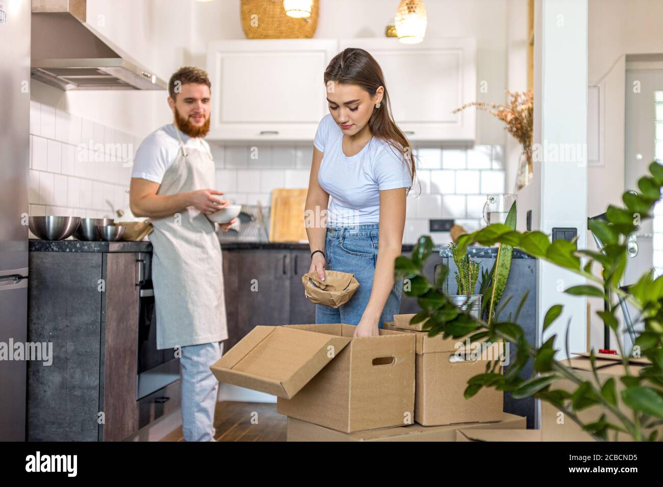 young caucasian happy couple unpacking cardboard boxes after moving in