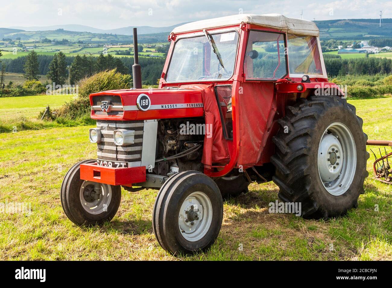 Drinagh, West Cork, Ireland. 12th Aug, 2020. Drinagh farmer George Wilson uses a 1970's Massey Ferguson 168 and a 1970's haybob to fluff the cut hay and narrow the swath before the hay is baled. Credit: AG News/Alamy Live News Stock Photo