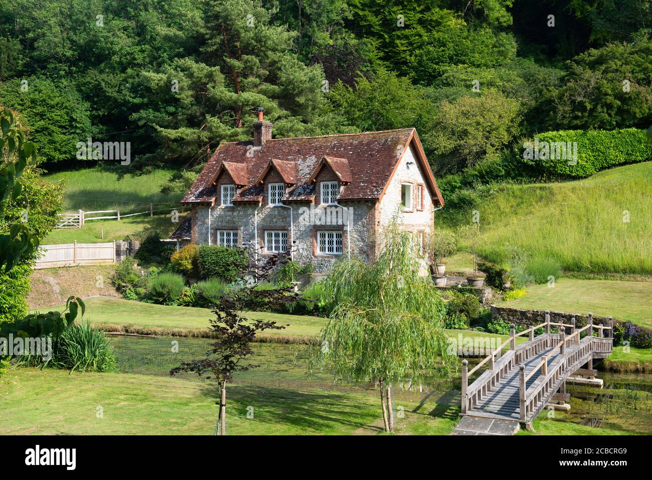 A large traditional flint, stone and red brick dwelling nestles at the base of the South Downs in West Sussex. England, UK Stock Photo