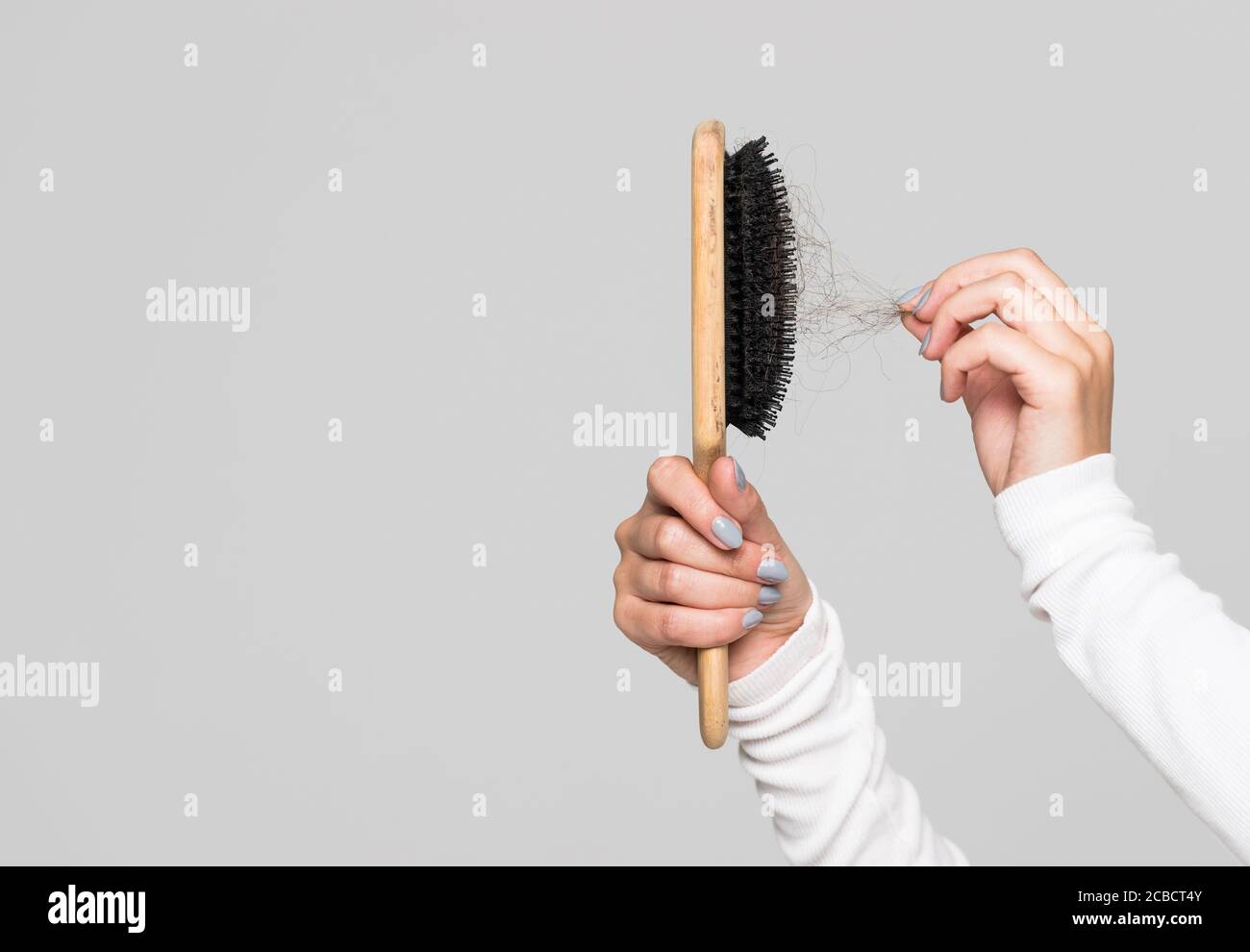 Hair loss problem, postpartum period, menstrual disorder, stress. Many hair fall after combing in hairbrush. Female untangles her hair with a comb, co Stock Photo