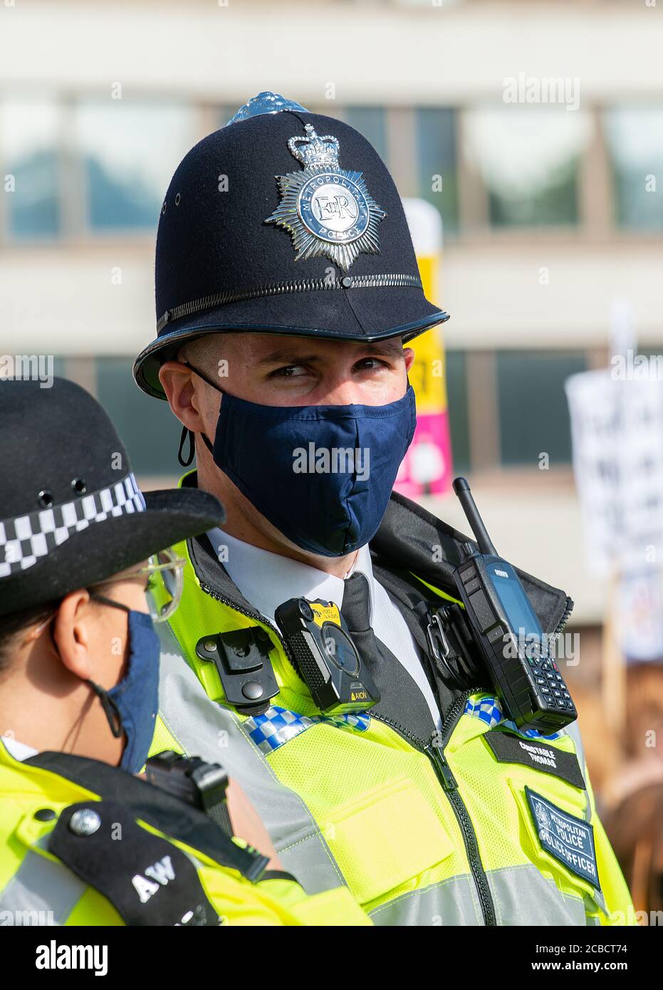 Two Metropolitan Police officers wearing blue face masks, while on duty during an NHS hospital workers protest demonstration in central London. Stock Photo