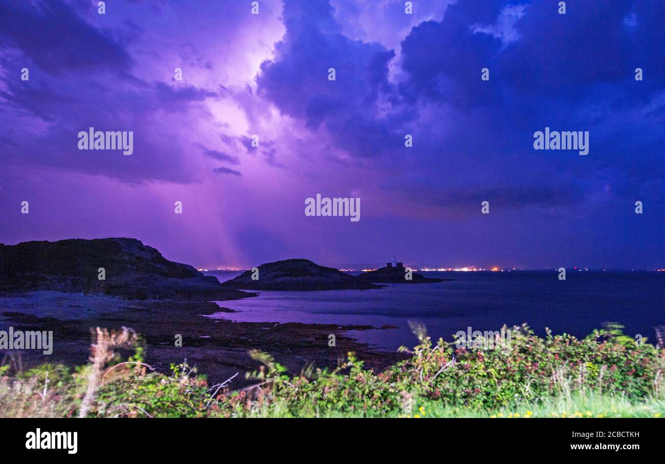 Mumbles Headland, Swansea, UK. 12th Aug, 2020. Sheet lightning fills the night sky with colour above the Mumbles Lighthouse at Bracelet Bay near Swansea this evening during a break in the hot weather. Credit: Phil Rees/Alamy Live News Stock Photo