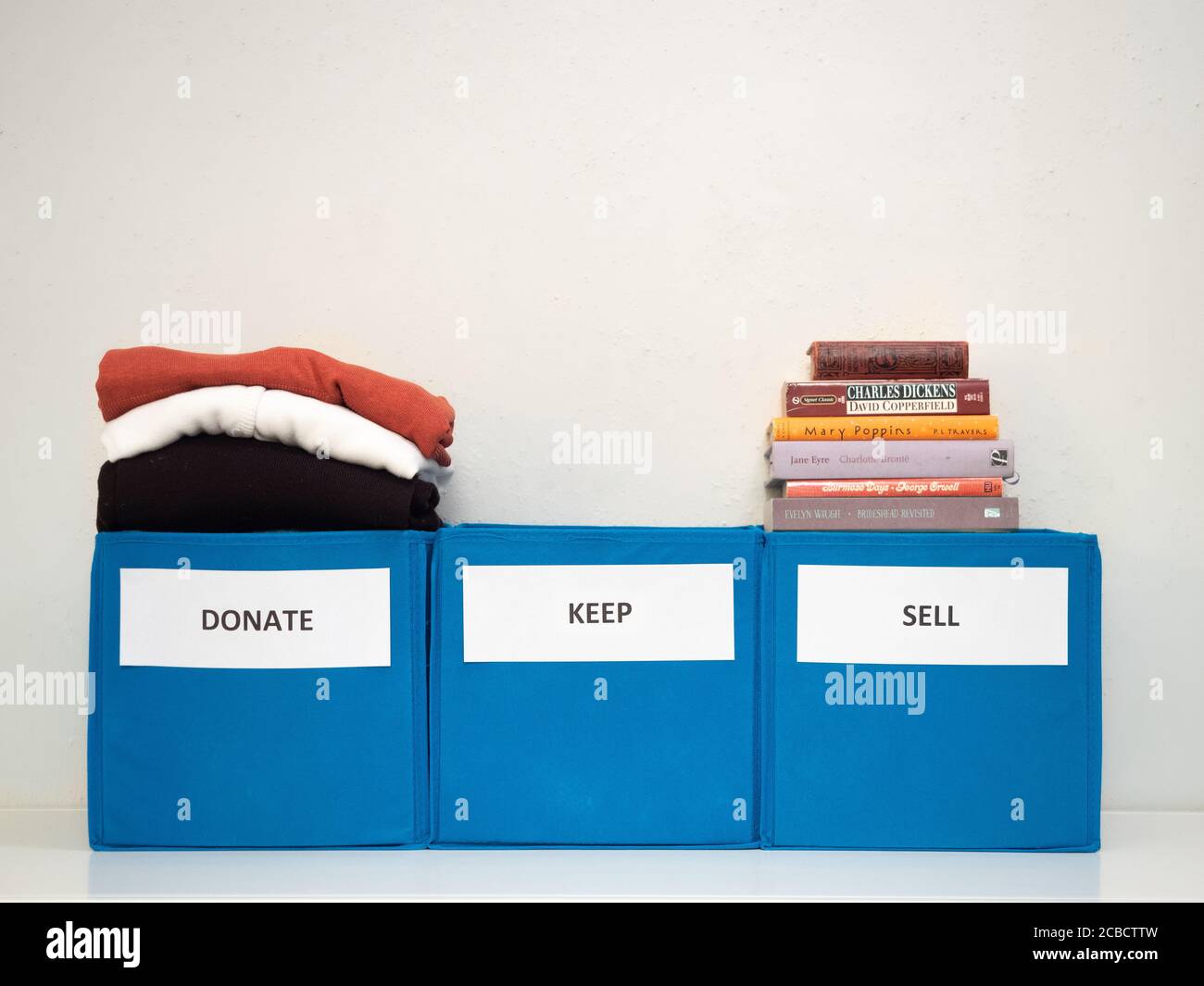 Three turquoise bins labeled donate, sell, and keep against a white