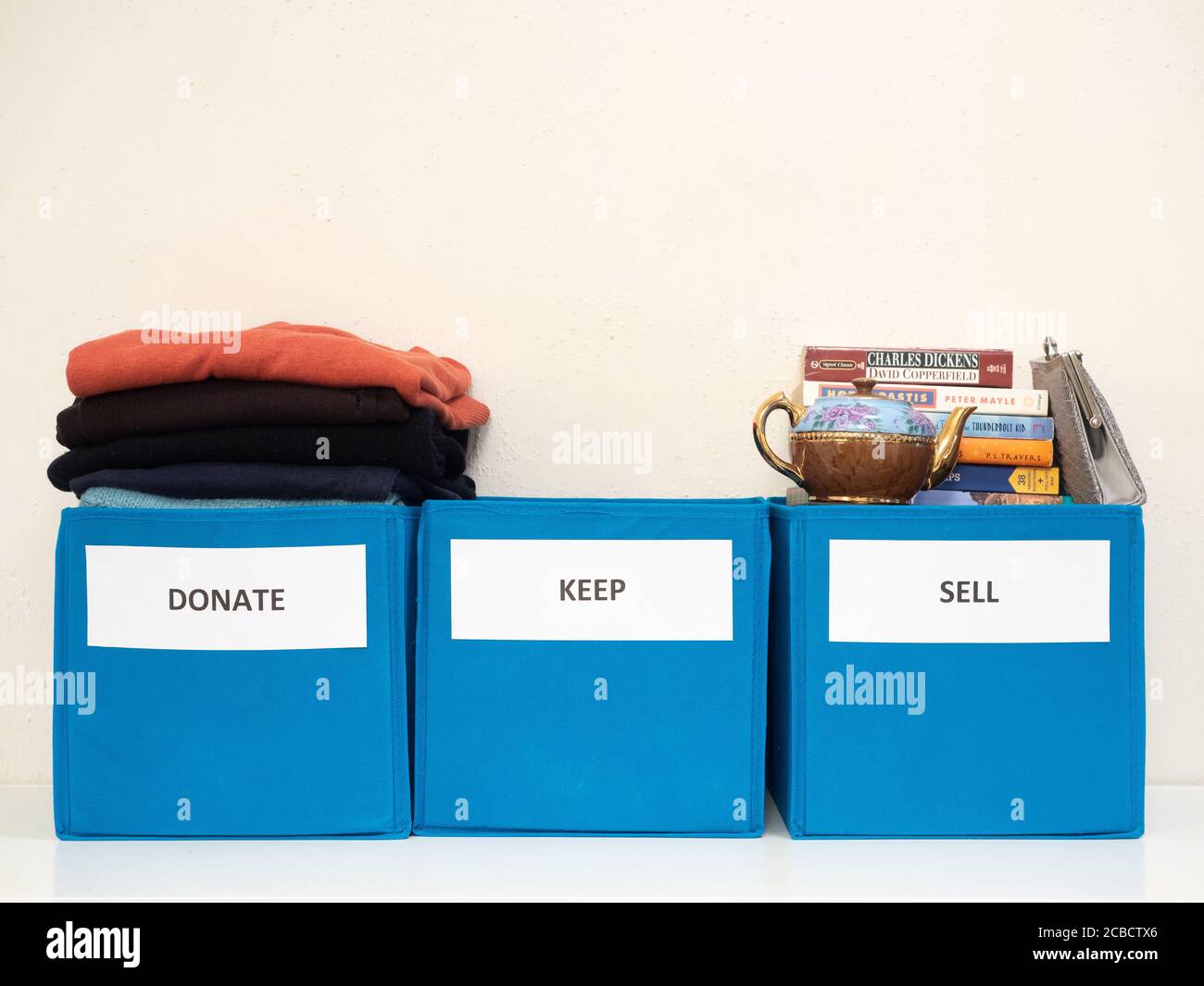 Three turquoise bins labeled donate, sell, and keep against a white