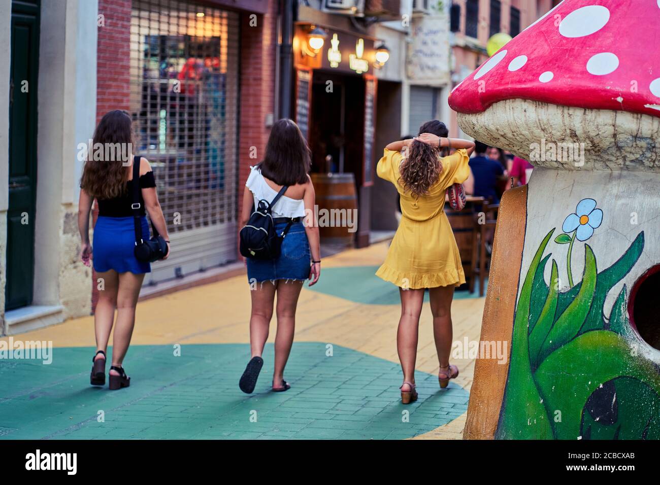 Three young women walk down San Francisco (mushroom) street in Alicante City, Spain, Europe, July 2020 Stock Photo