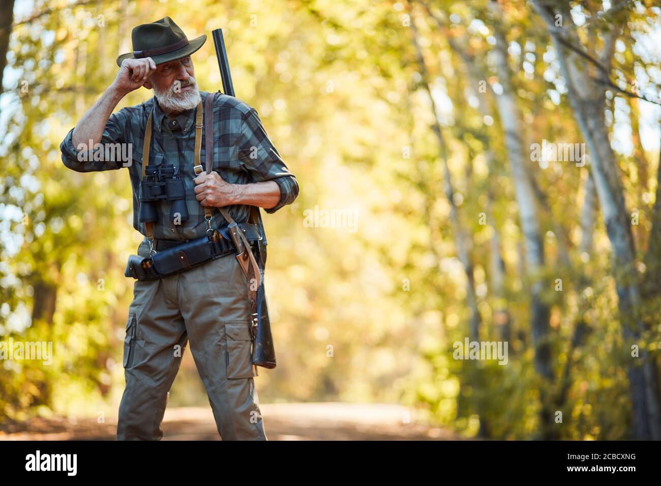 Bearded caucasian man in hunting clothes stand looking away. Forest