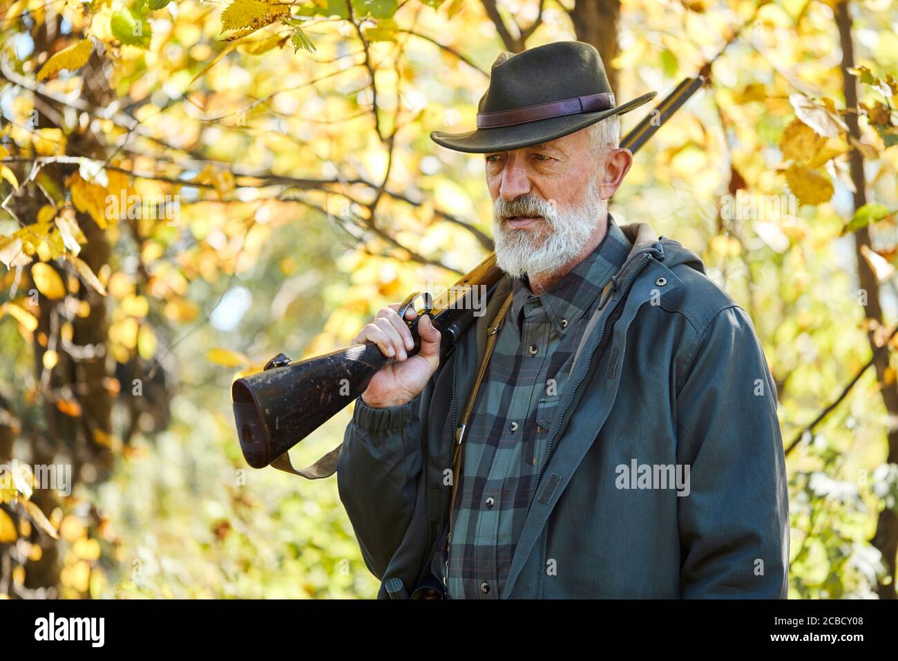 Forest hunting on animals. Senior man holding shotgun, Upset after hunting in forest Stock Photo