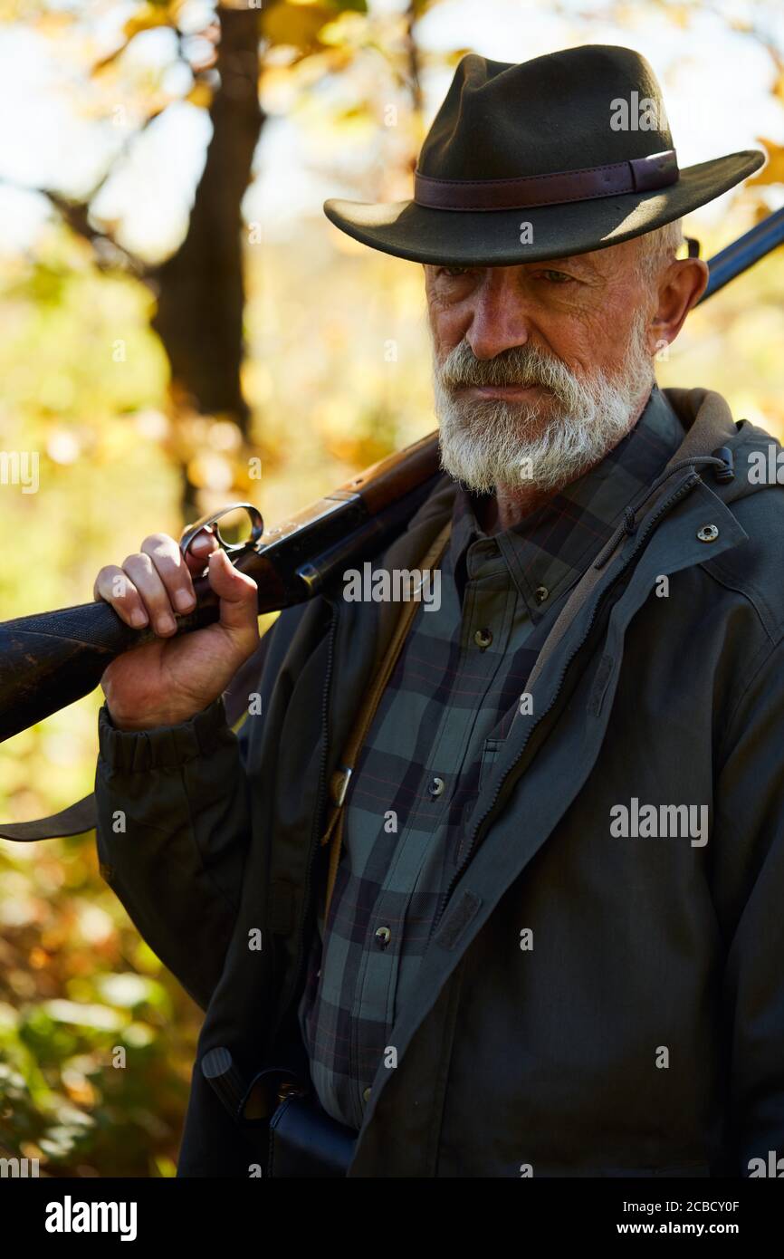 Senior caucasian man holding shotgun.Sad, serious after hunting in forest Stock Photo