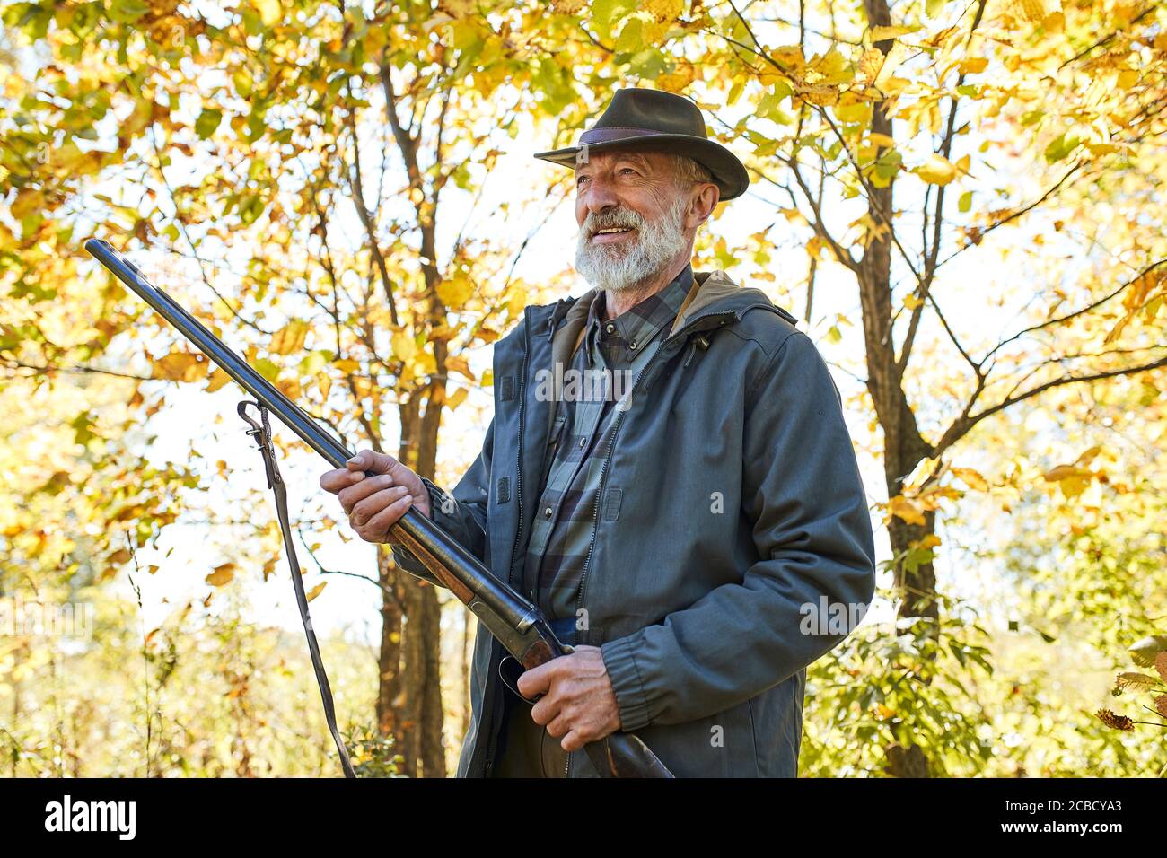 Senior caucasian hunter holding shotgun ready to shoot on wild animals