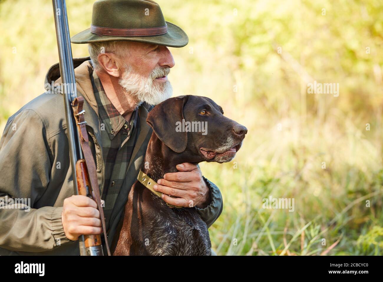 Caucasian mature man with gun and dog sit searching prey. Bearded