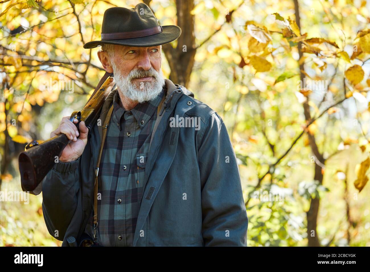 Forest hunting on animals. Senior man holding shotgun, look away. Excited after hunting in forest Stock Photo