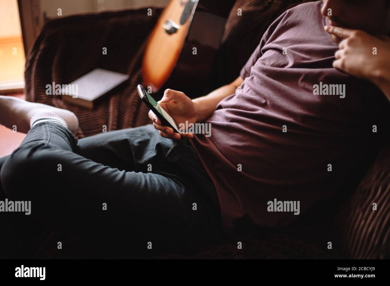 Thoughtful young man using smart phone while sitting at home Stock Photo