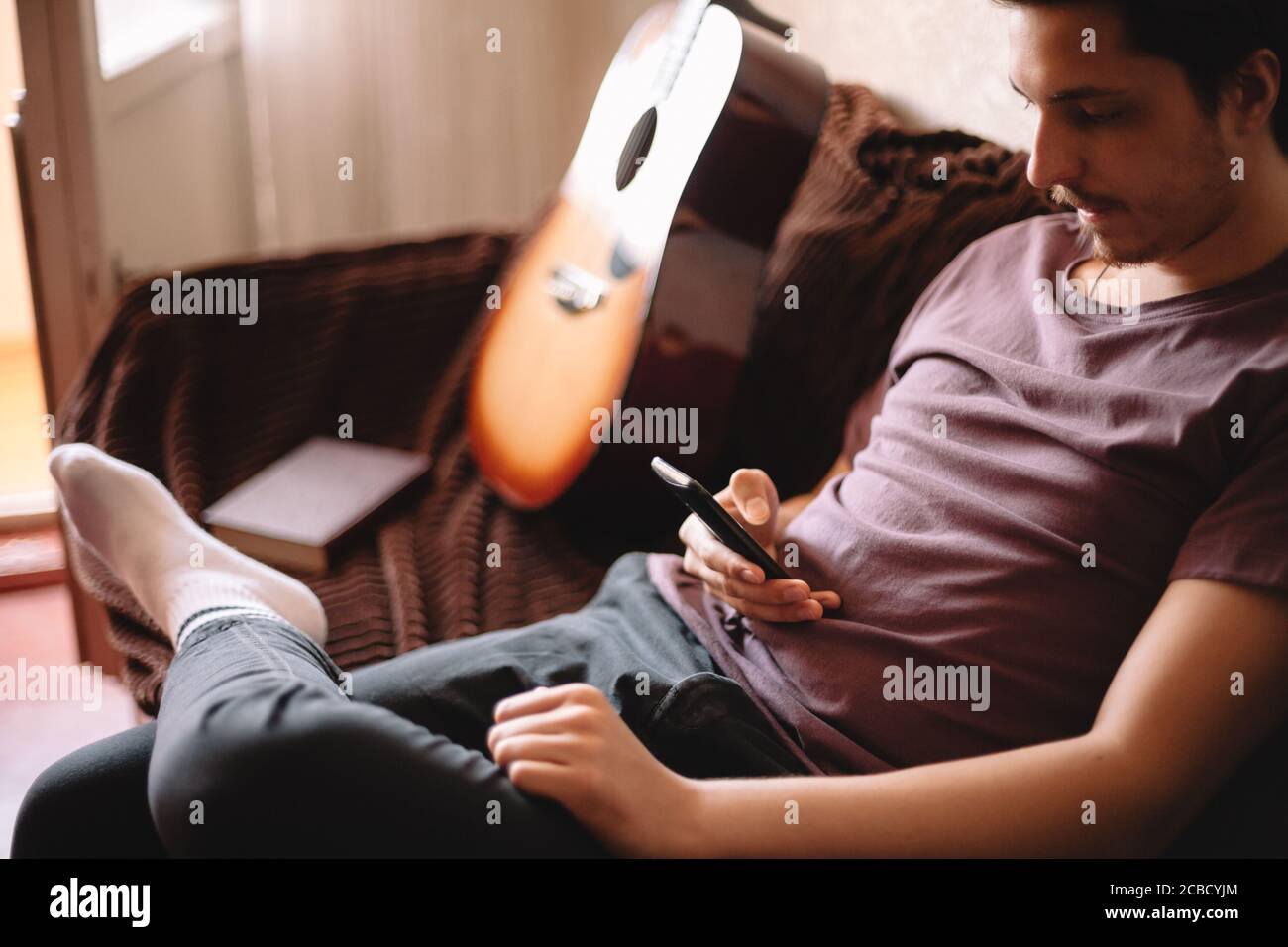 Serious young man using smart phone while sitting at home Stock Photo