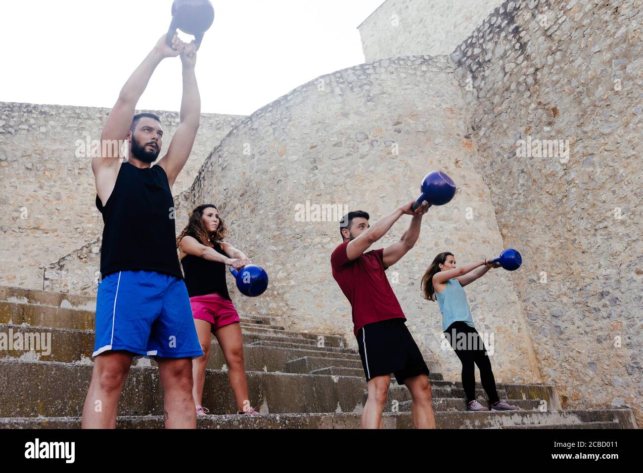 Athletes lifting a kettelbell crossfit weights in an urban enviroment
