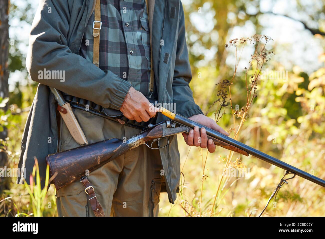 Man holding shotgun loading it. Forest background. Hunting, people concept Stock Photo